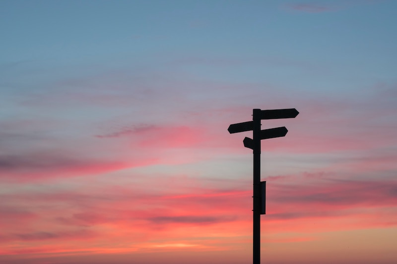 Image of sunset with directive signs in distance.